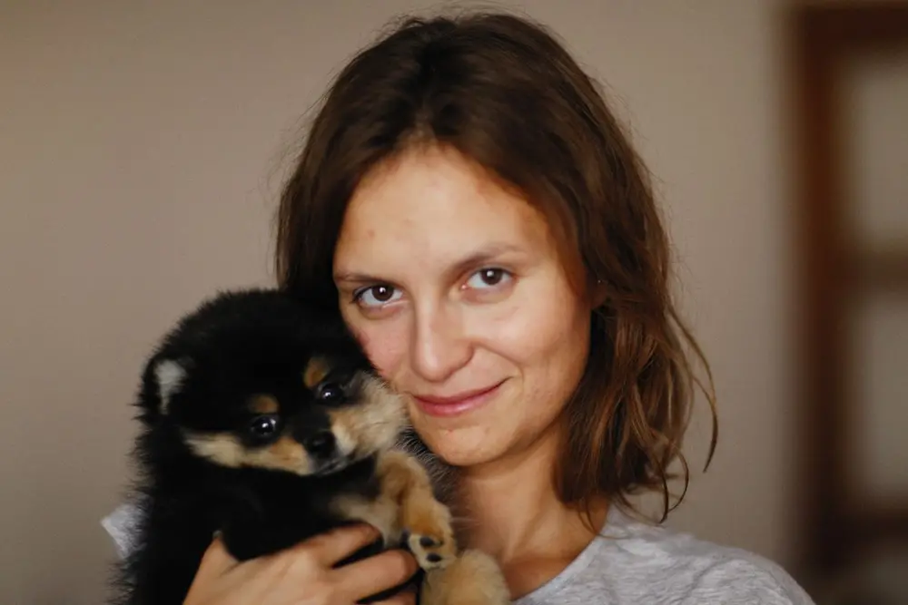 Жінка тримає на руках цуценя шпіца
