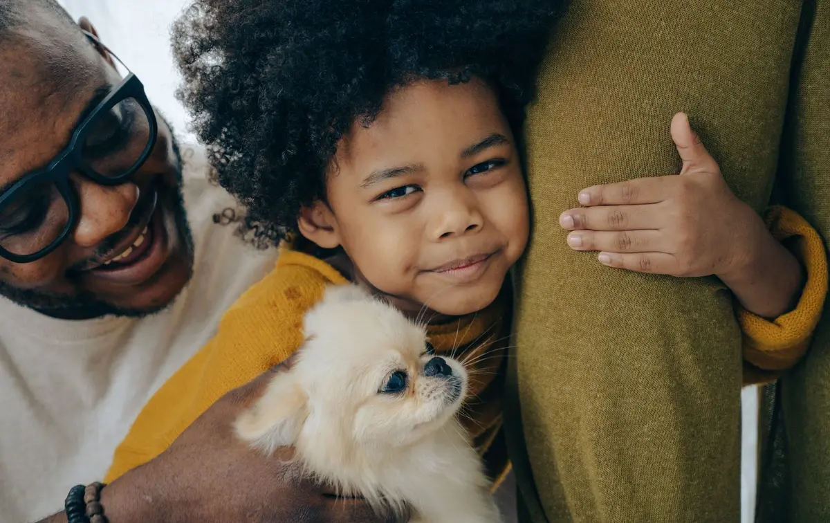 Тато з дитиною і маленьким собакою на руках удома